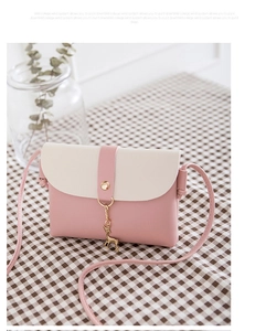 Detail of a mini pink and cream crossbody bag with a golden deer pendant on a checkered table
