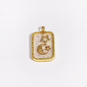 Detailed view of rectangular star and moon pendant with purple glitter inlay in gold frame