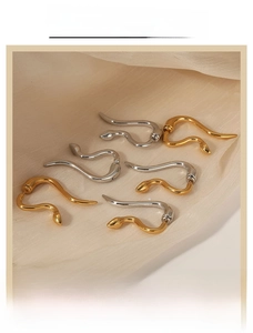 Detailed view of snake-shaped gold and silver earrings on elegant silk fabric