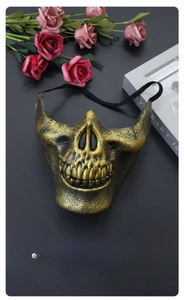 Close-up of golden skull mask with elastic strap near pink roses and a magazine