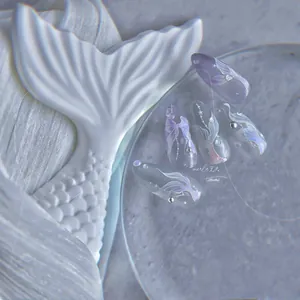 Detail of mermaid style press-on nails with 3D bows, pearls and fish tail texture