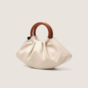 Detail of cream pleated cloud bag featuring retro wooden style resin handles