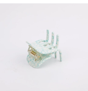 Detailed close-up of a white and blue marble acetate bow hair claw clip with a sturdy spring