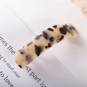 Close-up of a tortoiseshell acetate spring hair clip on a minimalist paper background