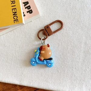 Close-up of cute Capybara riding a blue motorcycle keychain on a white canvas background