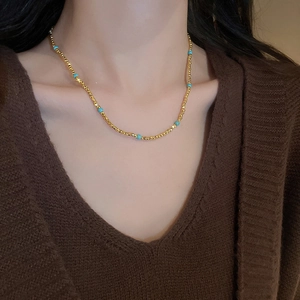 Détail d'un collier en acier inoxydable doré avec perles turquoise bleues sur le cou