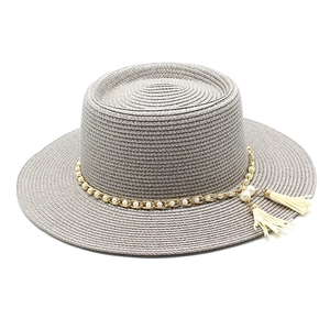 Détail d'un chapeau de paille gris avec chaîne dorée, perles et glands décoratifs