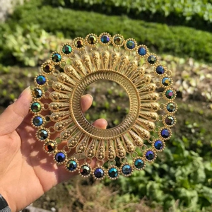 Close-up of golden metal circular wall decor with blue evil eye beads in hand
