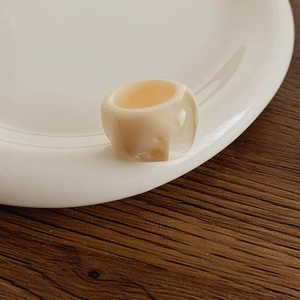 Detail shot of a cream resin ring with a glossy finish on a white ceramic plate