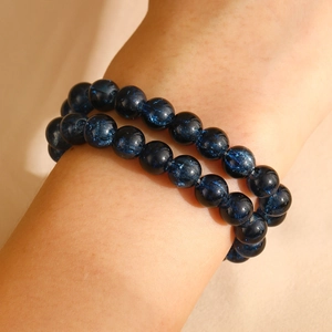 Detail van twee donkerblauwe sterrenhemel kralenarmbanden met sprankelende textuur