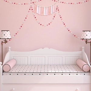 Close-up of pink and white pom-pom garland with tassels on a child room wall decoration