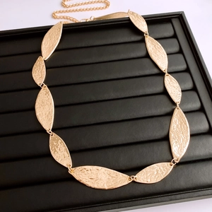 Detail of gold leaf-shaped waist chain with textured hammered finish on jewelry tray