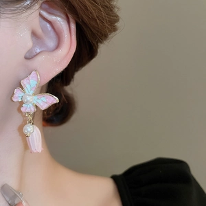 Gros plan sur des boucles d'oreilles papillon et tulipe avec perles, tons rose et bleu