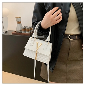 Detail of white leather handbag with gold V logo, fringe accents and quilted pattern