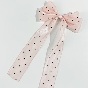 Detail of a pink polka dot mesh bow hair clip with elegant long hanging ribbons