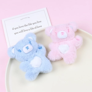 Cute pink and blue plush bear pendants with heart embroidery on a white decorative plate