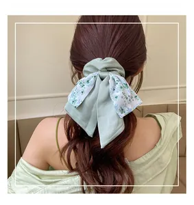 Detail of light green matte satin bow scrunchie with floral pattern on female hair