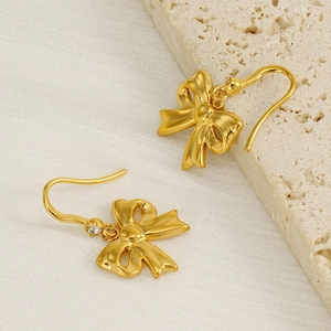 Elegant gold bow earrings with crystal diamond accents on minimalist stone display