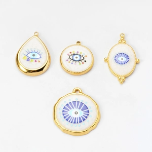 Detailed view of four white enamel evil eye pendants with gold plated irregular shapes