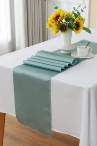 Detail of teal satin table runner showing smooth silky texture on white tablecloth