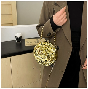 Detail of a metallic gold rose evening bag with bead handle and chain strap on a model
