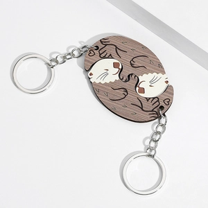 Detail of wooden interlocking otter charms with engraved finish and silver keychains