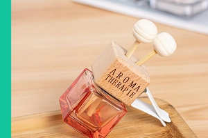Detail view of square glass perfume bottle with amber liquid and wooden vent clip