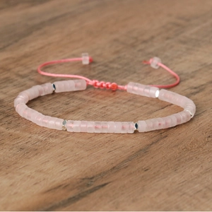 Macro detail of pink imperial stone beaded bracelet with silver rhombus spacers on wood