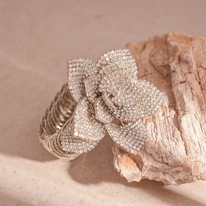 Detail showing the intricate floral design with white crystals on a silver metal bangle