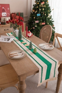 Detail of Christmas table runner with beige and green stripes and soft cotton tassels