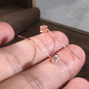Dettaglio degli orecchini a catena in oro rosa con zirconi brillanti e design lineare