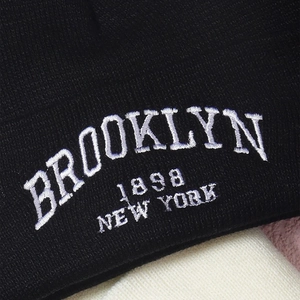 Detail of white Brooklyn New York embroidery on a black ribbed knit beanie hat