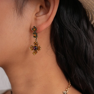 Close-up of vintage gold cross earrings with colorful gemstones and crystals