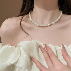 Close-up of elegant single-strand white pearl necklace worn on model for a refined look