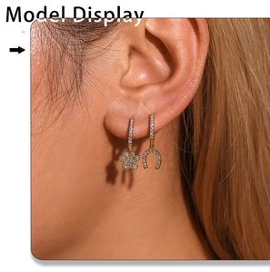 Macro shot of asymmetric gold-plated earrings with pavé zircon cat paw and horseshoe