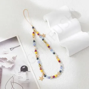 Detail of colorful beaded phone strap with gold stars on white minimalist background