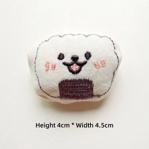Detail showing plush onigiri accessory with embroidery measuring 4cm high by 4.5cm wide