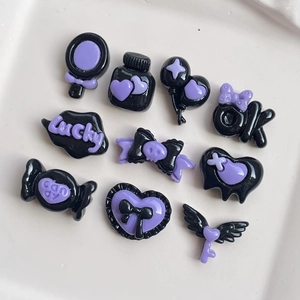 Flat lay of 10 black and purple resin gothic charms including hearts and magic bottles
