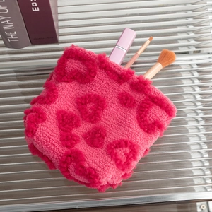 Plush rose pink makeup bag showing interior storage for lip gloss and cosmetic brushes