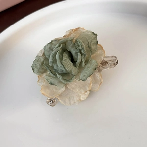 Detailed view of a gradient rose hair claw clip made of delicate mesh fabric in a white dish