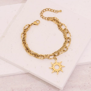 Vue macro d'un bracelet doré à maillons superposés avec un pendentif soleil poli
