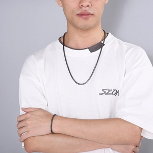 Detail of matte black dragon bone chain necklace and bracelet set on male model