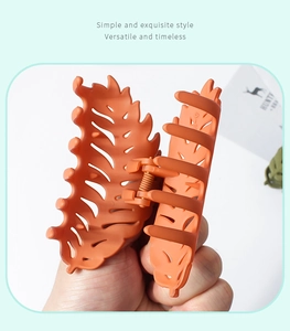 Detail of leaf-shaped matte claw clip in brick red with internal spring structure