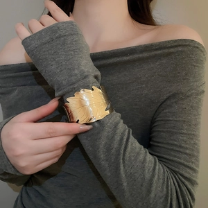 Close-up of a gold-finish irregular leaf-shaped open cuff bracelet on a model wrist