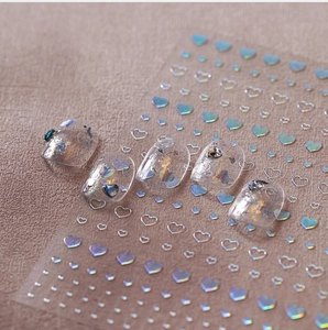 Macro view of holographic heart nail stickers with rose gold laser effect on display