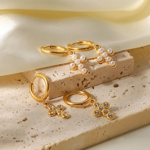 Macro view of gold stainless steel cross earrings with pearls and crystals