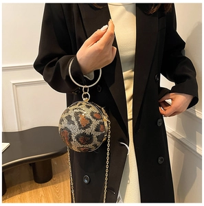 Model wearing a spherical evening bag with leopard sequins and a round metal handle