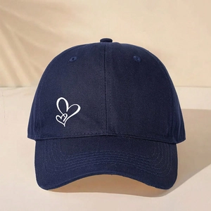 Detailed view of deep blue baseball cap featuring white double heart print and reinforced brim