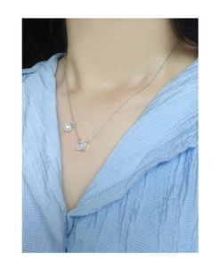 Detailed view of S925 silver necklace with square zircon and round pearl on a model