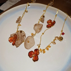 Detailed macro view of amber resin flower pendants and soft fabric leaves on gold chains